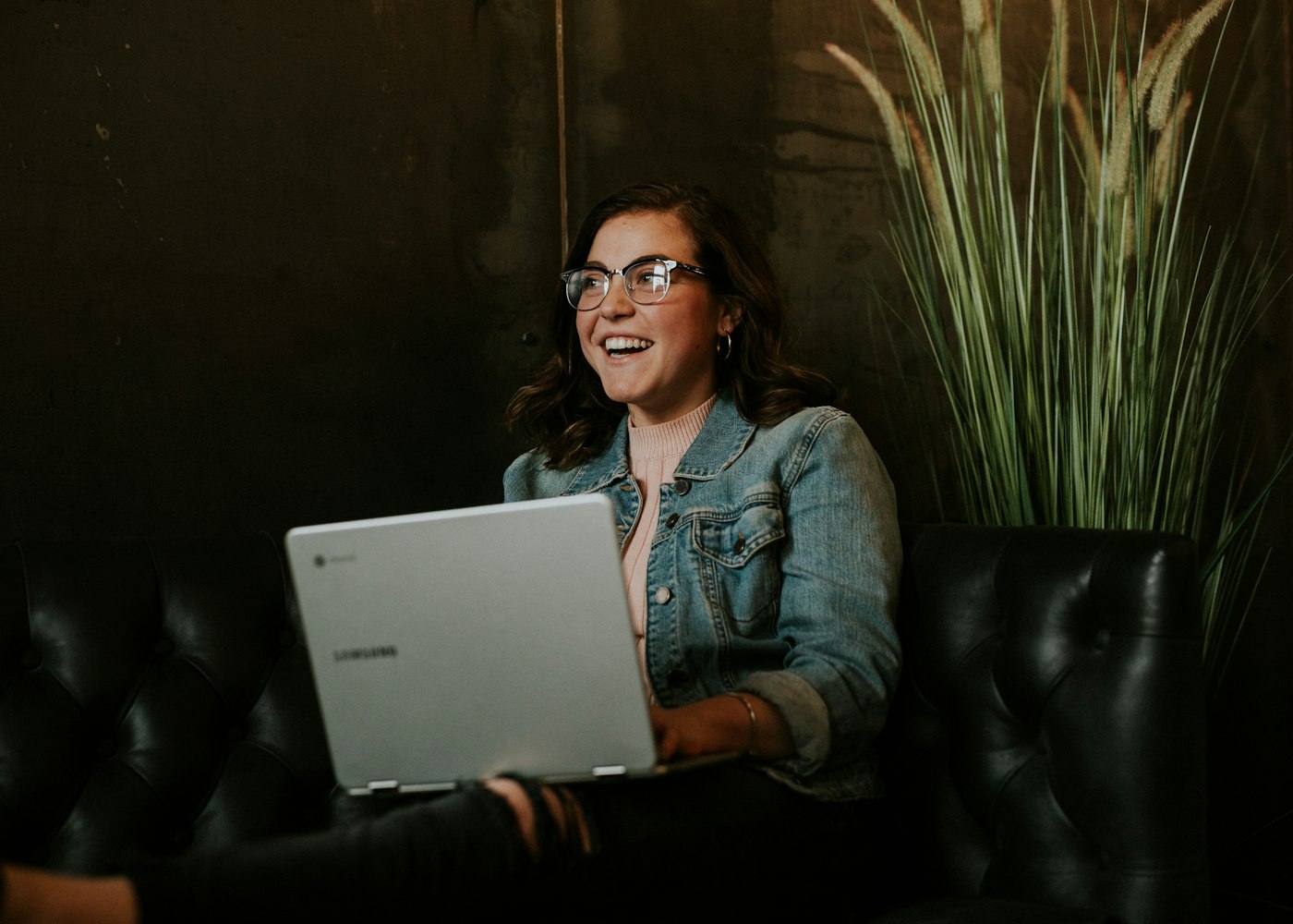 A woman laughing as she works on a laptop